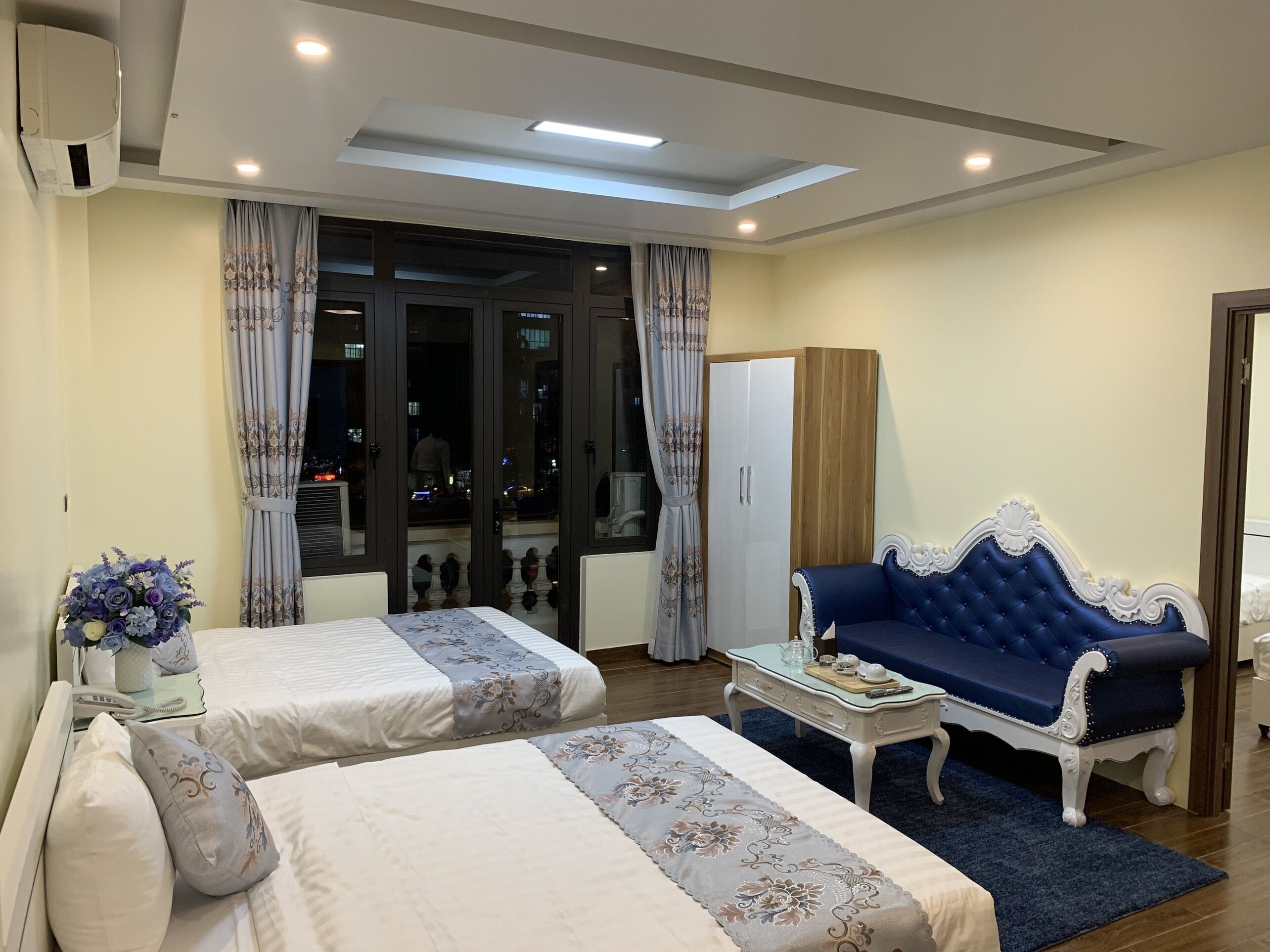 A hotel room with two beds, a sofa, a small table, and a wardrobe.