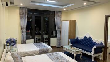A hotel room with two beds, a sofa, a small table, and a wardrobe.