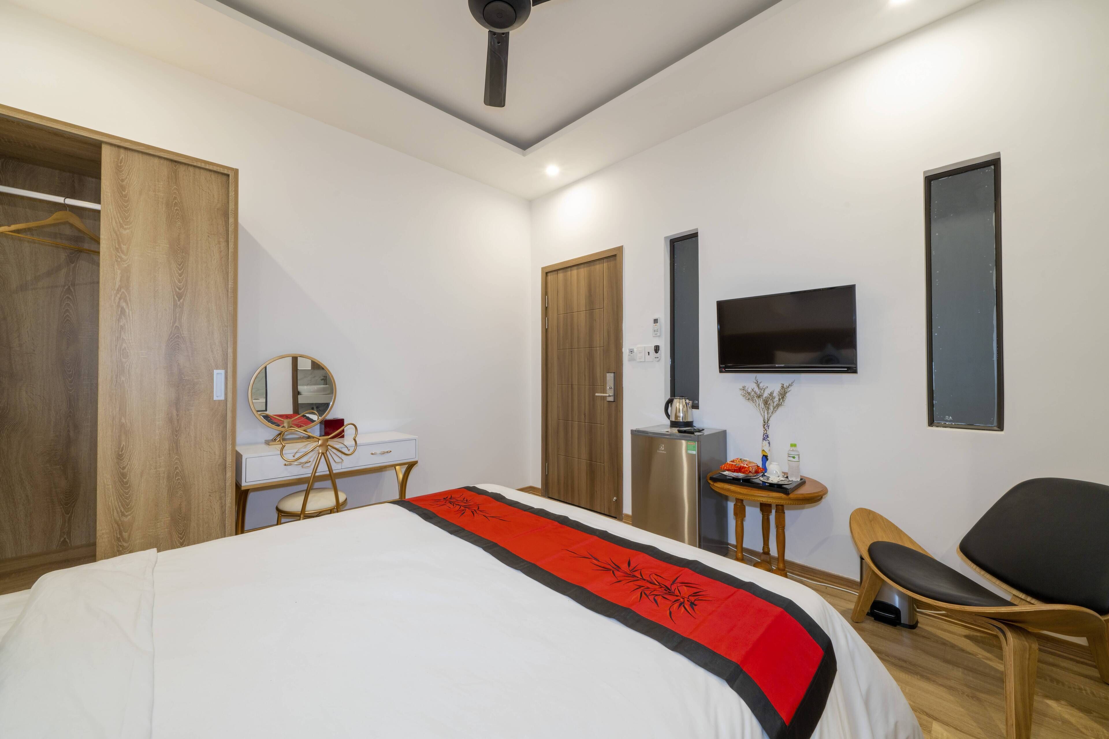 Une chambre d’hôtel moderne équipée d’un lit, d’un bureau, d’une chaise, d’une télévision et d’une armoire.