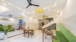 A modern hotel lobby with marble flooring, wooden furniture, ceiling fans, and potted plants. - Q Villa Hoi An (Da Nang)