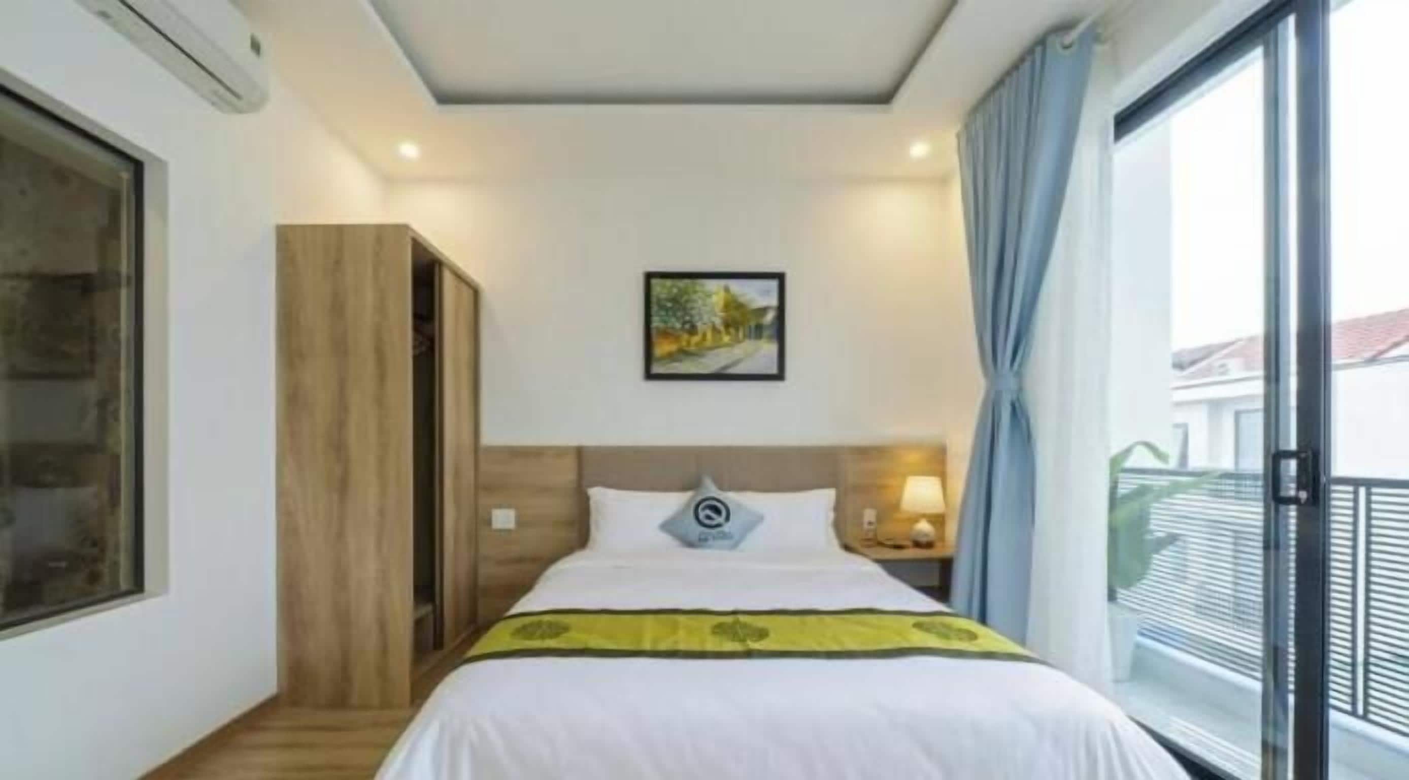 A hotel room with a bed, a nightstand, a window, and a view of the outside.