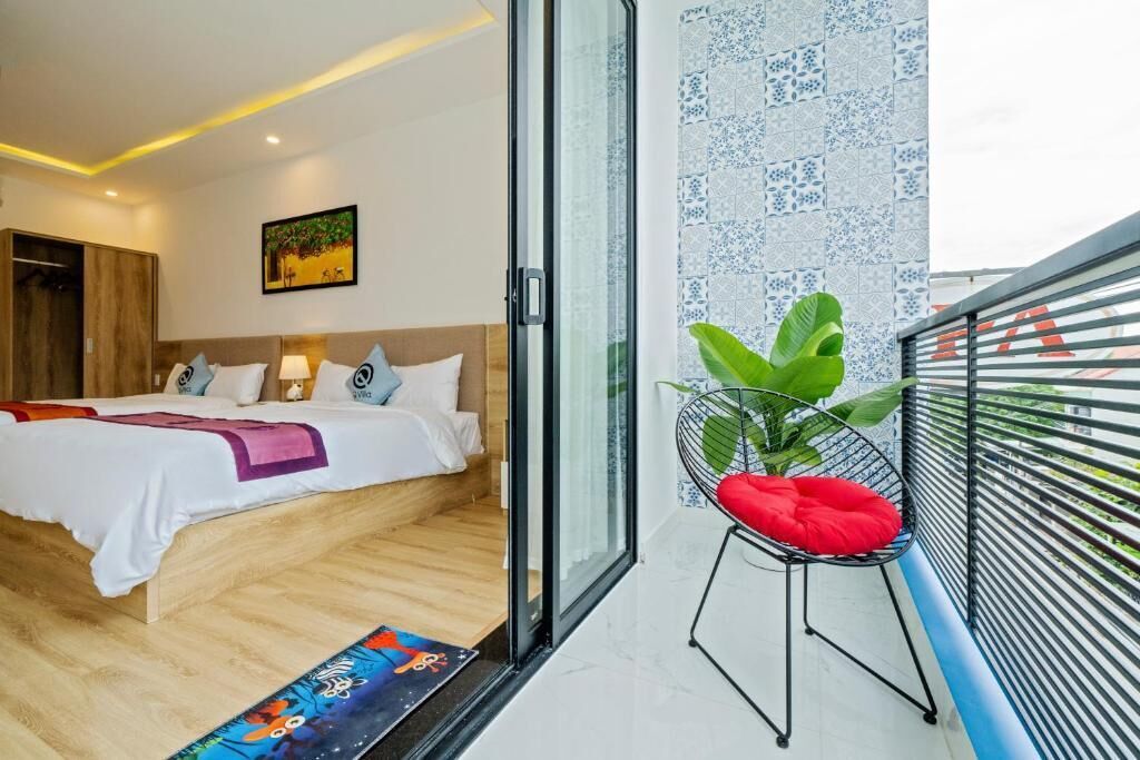 Una habitación de hotel con cama, una silla, ventana y balcón.