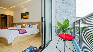 Una habitación de hotel con cama, una silla, ventana y balcón.