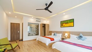A hotel room with two beds, a ceiling fan, a painting, and a wooden door. - Q Villa Hoi An (Da Nang)
