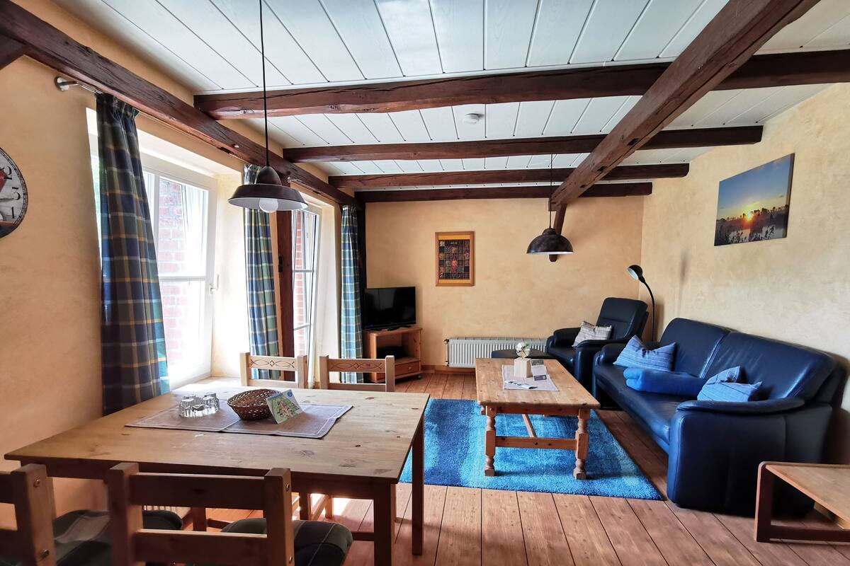 Ein gemütliches Wohnzimmer mit einem Holztisch, einem blauen Sofa und einem Fernseher.