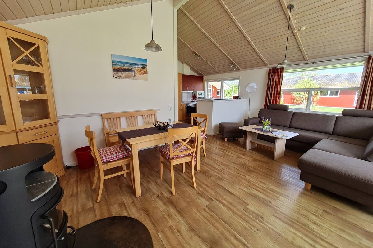 Ein gemütliches Wohnzimmer mit Holzmöbeln, einem Esstisch und einer Couch.