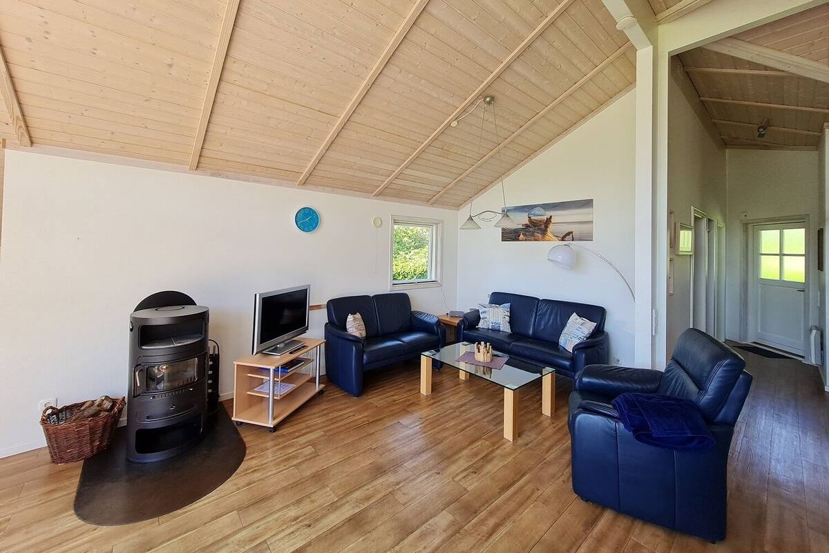 Ein geräumiges Wohnzimmer mit Holzboden, Kamin, Fernseher und einer Couch.