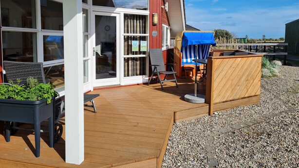 Une terrasse en bois avec des meubles d’extérieur, un espace salon couvert et une vue sur le paysage environnant.
