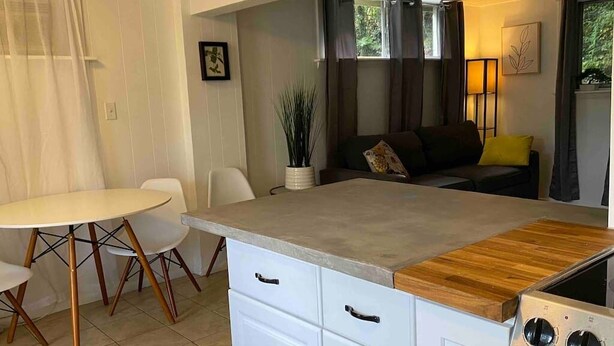 A compact kitchen with a dining table, white cabinets, and a wooden countertop.