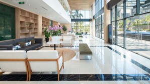 Eine großzügige Lobby mit modernem Design, ausgestattet mit einer Rezeption, einer Sitzecke mit Sofa und Sesseln, einem Couchtisch und einer Zimmerpflanze.