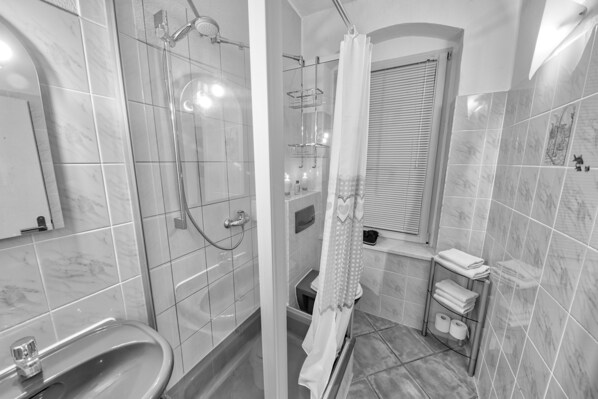 A modern bathroom with a glass-enclosed shower, a freestanding bathtub, and a towel rack with neatly folded towels.