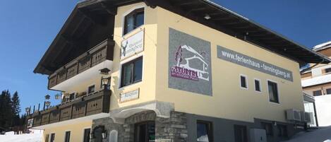 A multi-story building with a reception area, a sign for 'Chalet Fanningberg', and a website address 'www.ferienhaus-fanningberg.at'.