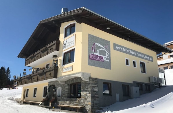 Ein mehrstöckiges Gebäude mit einer Rezeption, einem Schild mit der Aufschrift 'Chalet Fanningberg' und der Internetadresse 'www.ferienhaus-fanningberg.at'.