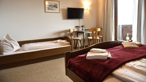 A hotel room with a bed, a desk, a chair, a television, and a window with curtains. - Ferienhaus Fanningberg (Weisspriach)