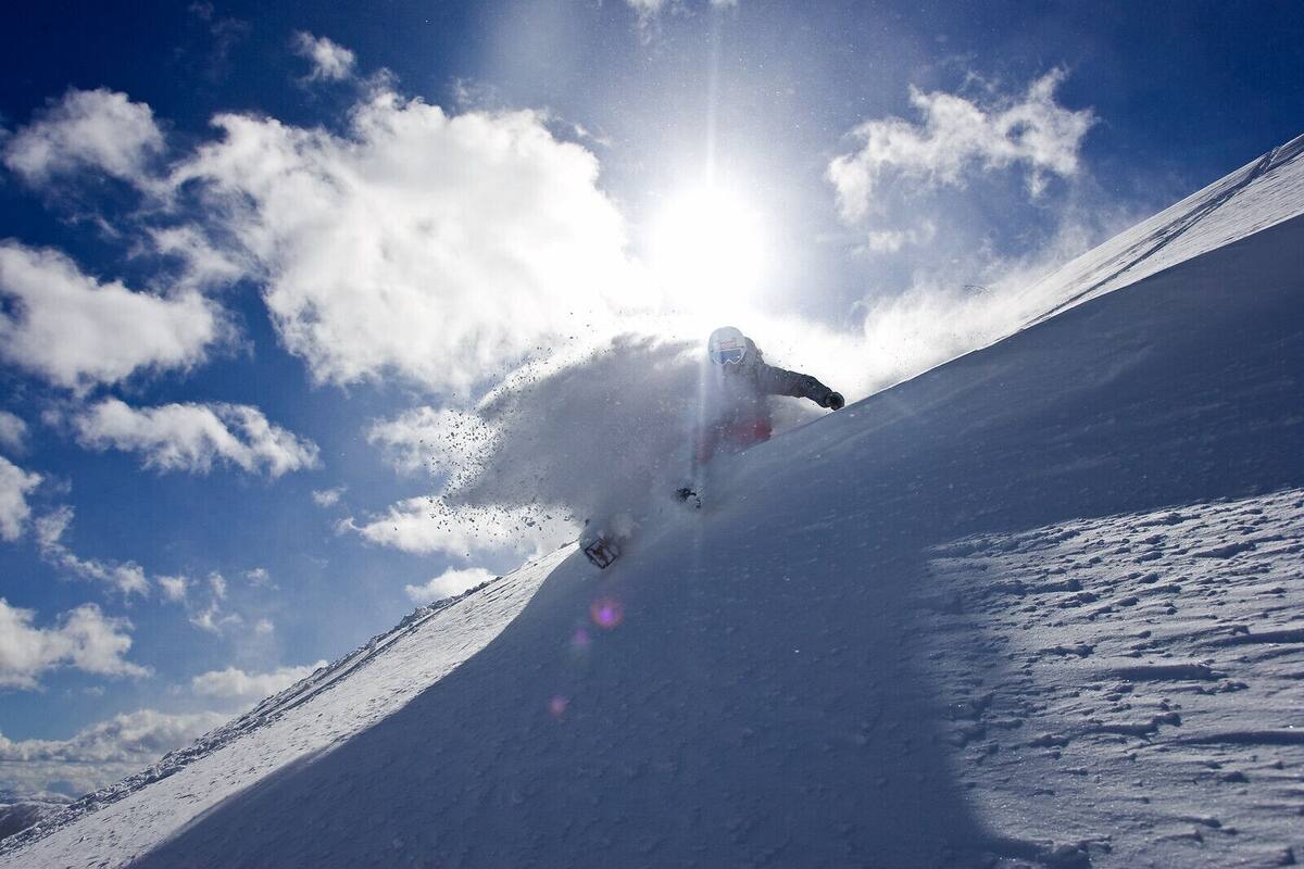 En snowboardåkare som åker nedför en snötäckt sluttning och gör snygga svängar.