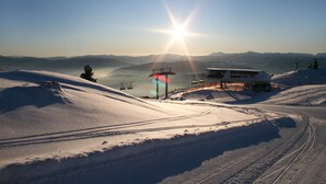 A snow-covered ski slope with a ski lift, a chairlift, and a building with a snow-covered roof. - Ferienhaus Fanningberg (Weisspriach)