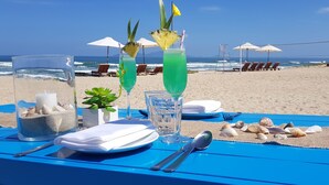 Une table de plage avec des boissons, un pichet et une assiette contenant des couverts.