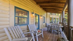 A log cabin with a porch featuring wooden chairs and a table. - Views, privacy, Kids Playhouse, Easy Access, Fast WiFi! Gated community (Waynesville)