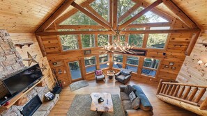 A log cabin interior with a fireplace, seating area, and large windows. - Views, privacy, Kids Playhouse, Easy Access, Fast WiFi! Gated community (Waynesville)