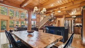 A spacious wooden interior with a large dining table, a kitchen area, and a staircase leading to an upper level. - Views, privacy, Kids Playhouse, Easy Access, Fast WiFi! Gated community (Waynesville)