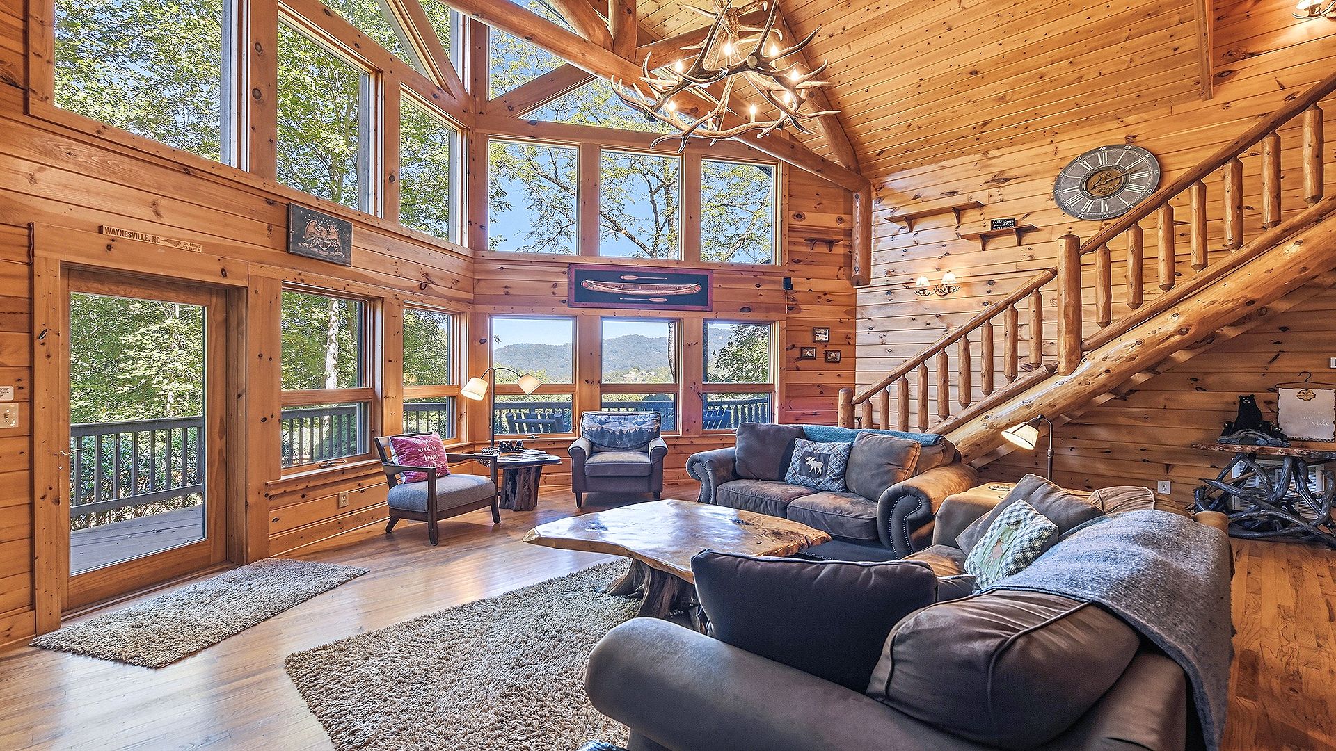 A spacious cabin interior with a large living area, wooden walls, and a staircase.