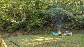 A backyard with a wooden deck, a fire pit, and a bench. - Views, privacy, Kids Playhouse, Easy Access, Fast WiFi! Gated community (Waynesville)