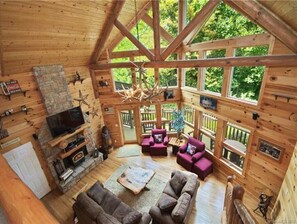 Cozy cabin with a fireplace, comfortable seating, and forest views.