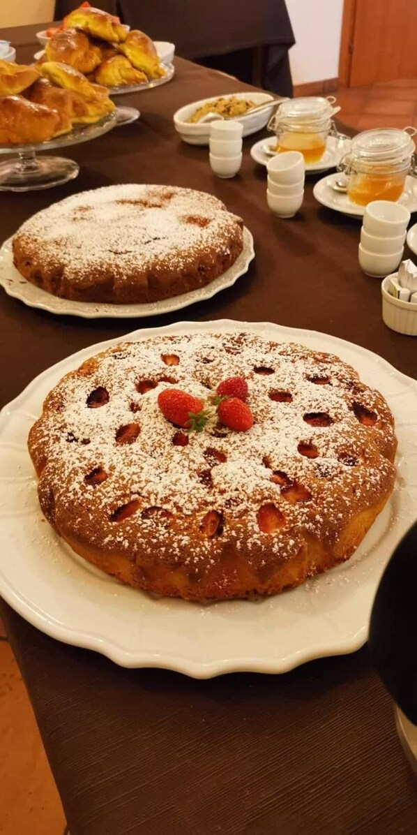 A round cake with strawberries and powdered sugar on a white plate. - Il Sentiero degli Ulivi (Santa Venerina)
