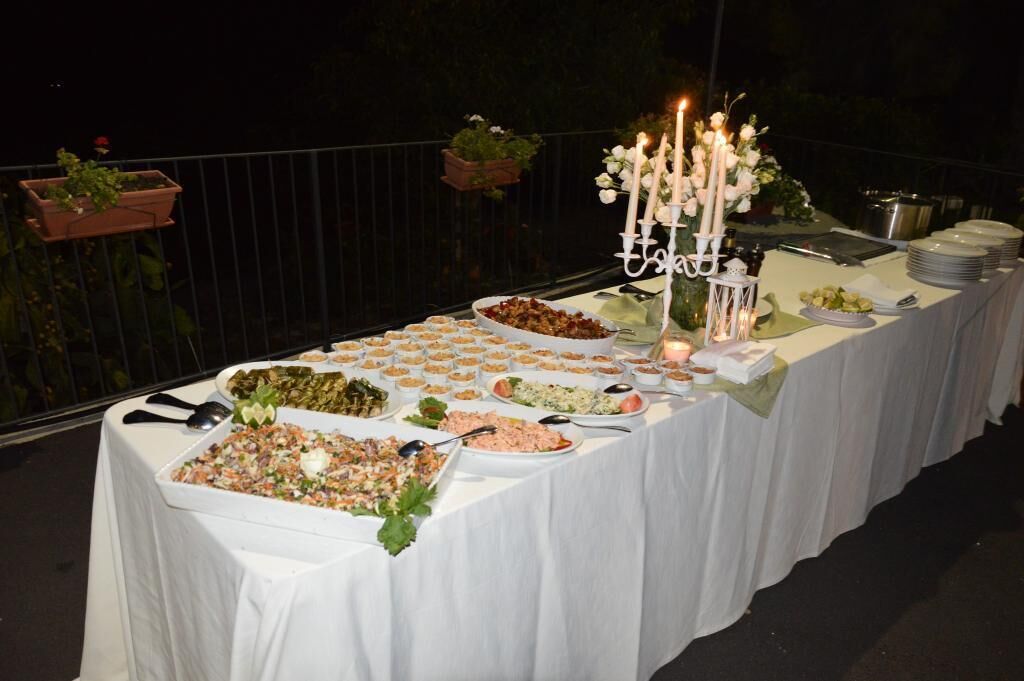 A buffet table with various dishes, a candelabra with candles, and a white tablecloth.