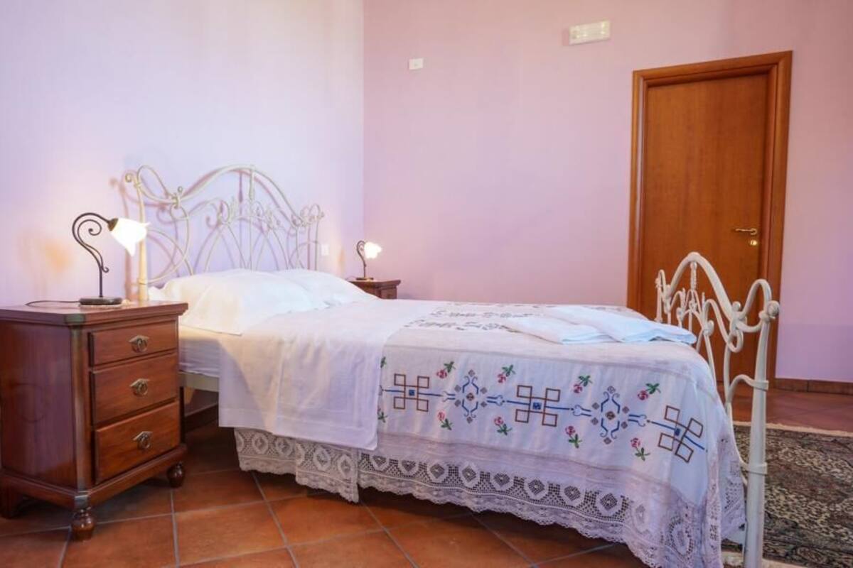 Un dormitorio con una cama, un aparador de madera, una mesita de noche y una puerta.