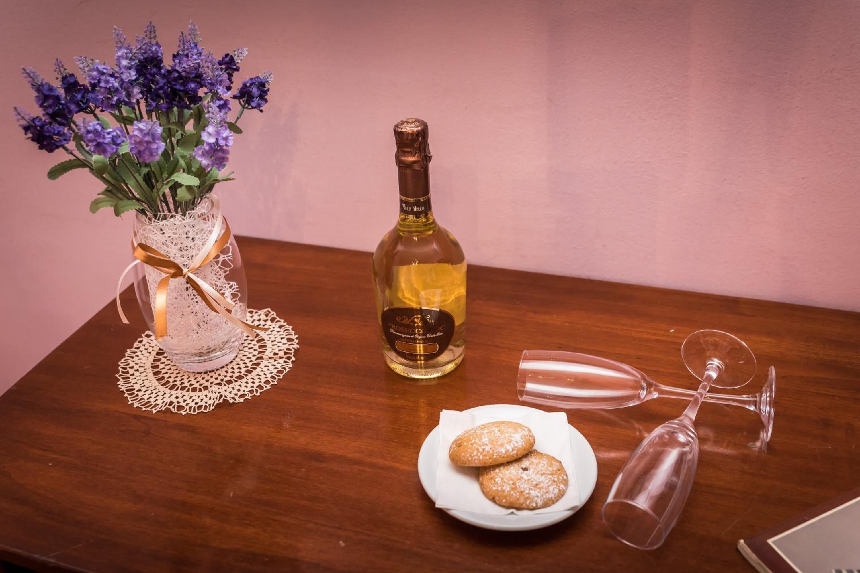 Een tafel met een fles wijn, een glas en een bord met koekjes.