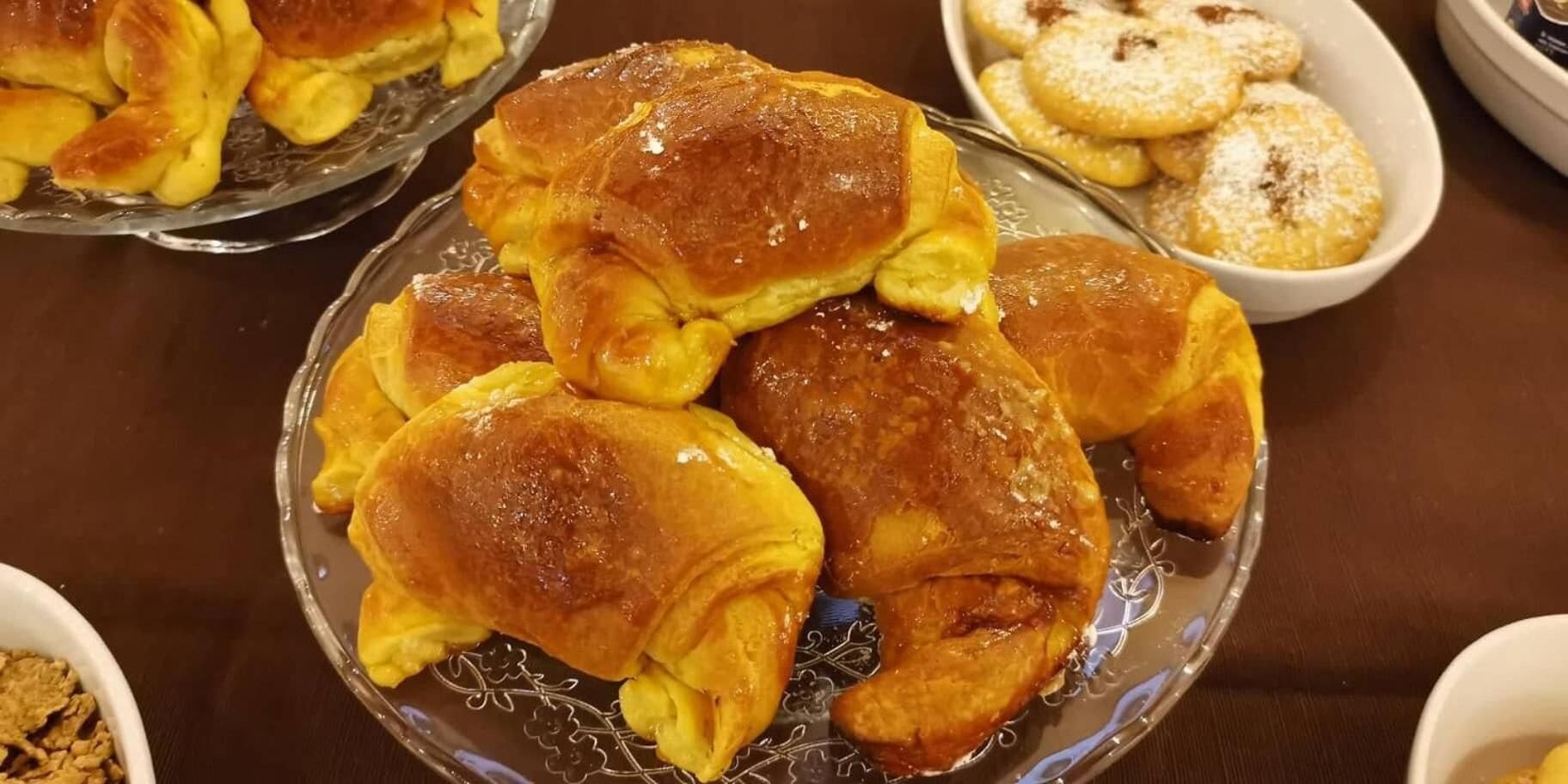 Ein Teller mit goldbraunen Gebäckstücken, vermutlich Croissants, auf einer Glasplatte.