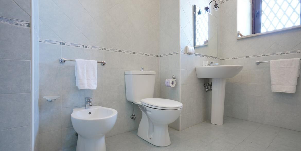 Un baño con inodoro, bidé y lavamanos.