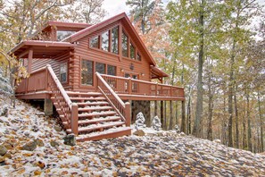 Eine Blockhütte mit Balkon, Treppe und Blick auf den Wald.