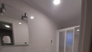 Un baño moderno con lavamanos, inodoro y ducha blancos.