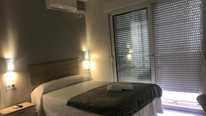 Un dormitorio moderno con cama, mesitas de noche y una ventana con persianas.