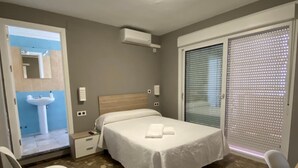 Un dormitorio con una cama, una silla, un escritorio, una ventana con persianas y un equipo de aire acondicionado.