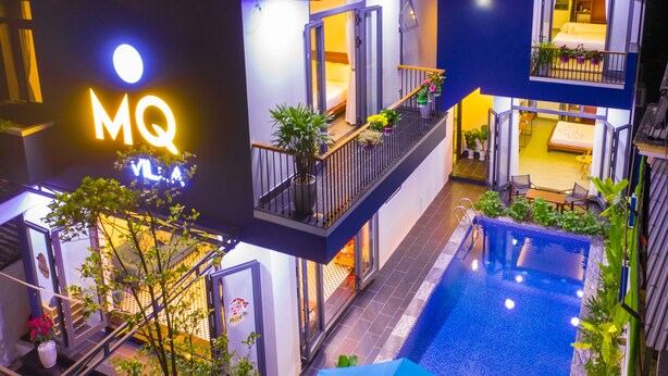 A multi-story hotel with a pool, balconies, and indoor plants. - MQ Villa (Da Nang)