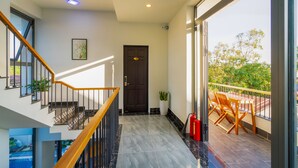 A modern interior with a staircase, a door, and a balcony with outdoor furniture. - MQ Villa (Da Nang)