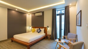 A modern hotel room with a large bed, a small table, two chairs, and a view of the outdoors. - MQ Villa (Da Nang)