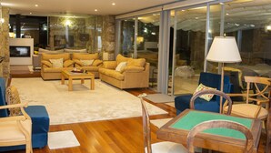 Un salon moderne avec un ensemble de canapés, une table basse en bois et une porte vitrée donnant sur un balcon.
