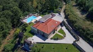 Vue aérienne d’une maison avec une piscine, un patio couvert et un jardin.