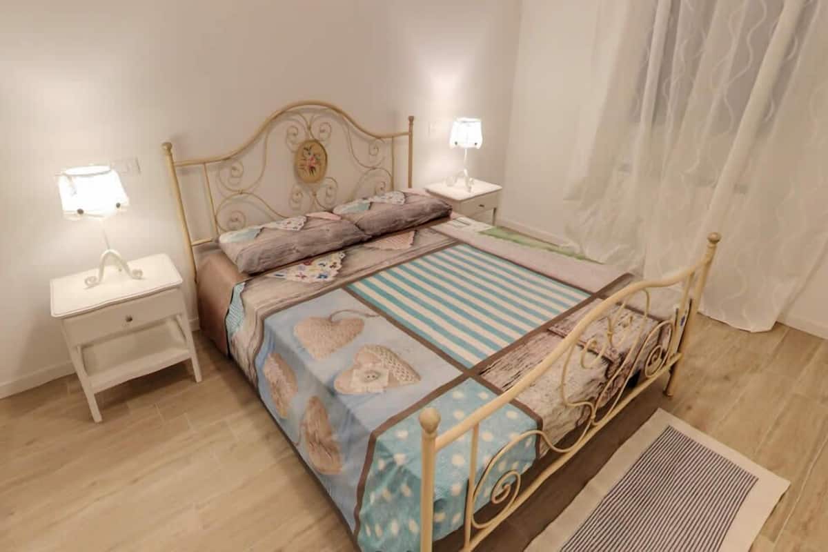 Un dormitorio ordenado con una cama, dos mesitas de noche y una mesilla.
