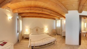Een slaapkamer met een houten plafond, een bed, nachtkastjes en een nachtkastje.