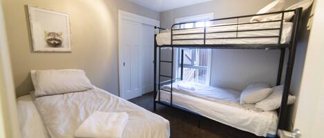 A bunk bed room with a door, a framed picture on the wall, and a window.