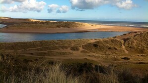 Eine Küstenlandschaft mit Dünen, einem Strand und einem Fluss.