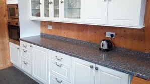 Eine Küche mit weißen Schränken, Granit Arbeitsplatten und Holzvertäfelung.