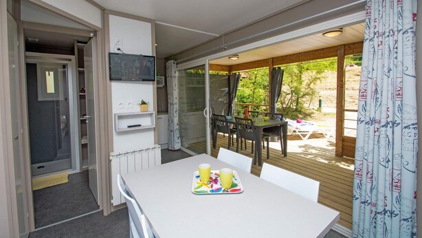 A compact kitchenette with a built-in microwave, a small shelf with a plant, and a table with a tray of colorful cups. - Camping Le Vieux Colombier (Moustiers-Sainte-Marie)