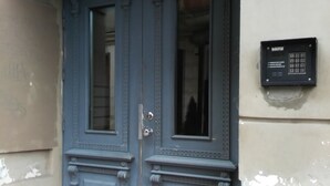 Une porte à deux battants, dotée d’un clavier pour le verrouillage, intégrée à un immeuble à la façade sobre.