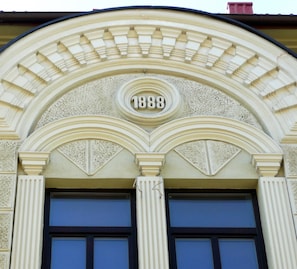 A building facade with a classical architectural style, featuring a prominent arched entrance with the year 1888 inscribed above. - Like Home Apartments (Vilnius)